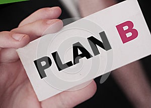 Plan B words on card in hand of businessman wearing suit and tie. Alternative business concept