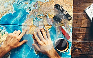 Plan Of Trip Destination. Mens Hands On A Paper Map Of The World Indicate The Final Destination, Top View.