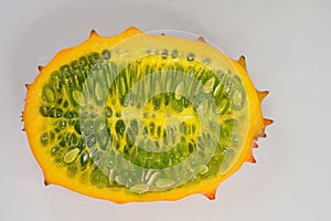 Plan view of a ripe Kiwano or Horned Melon fruit, sliced length-wise, on white background