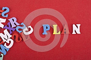 PLAN word on red background composed from colorful abc alphabet block wooden letters, copy space for ad text. Learning english