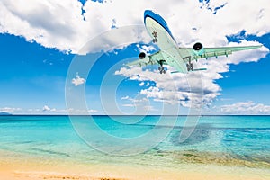 Plane above Caribbean Sea and beach. Travel and air transportation background.