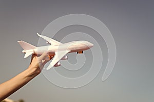 Plane in female hand clear blue sky background copy space. Travel and vacation. Book tickets now. Toy white plane fly