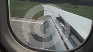 A plane with a flap lowered on the wing lands on the runway, slows down