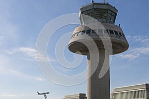 A plane flies next to the control tower at Barcelona Airport, Sp