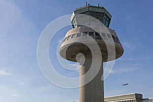 A plane flies next to the control tower at Barcelona Airport, Sp