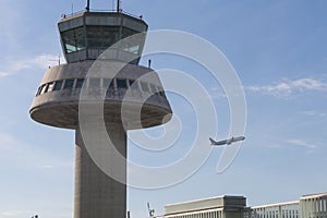 A plane flies next to the control tower at Barcelona Airport, Sp