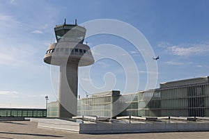 A plane flies next to the control tower at Barcelona Airport, Sp