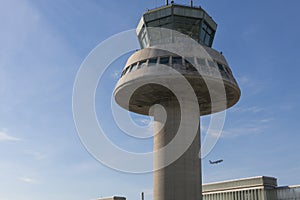 A plane flies next to the control tower at Barcelona Airport, Sp