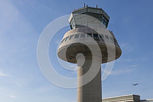 A plane flies next to the control tower at Barcelona Airport, Sp