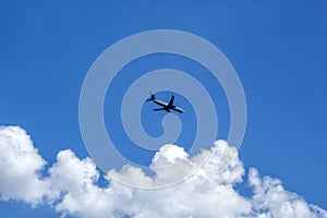 The plane flies in the sky with clouds.