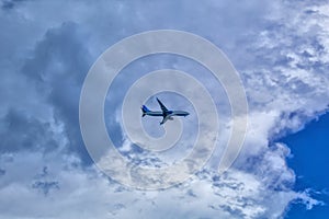 The plane flies in the sky with clouds.