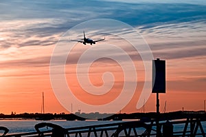 The plane flies to the airport over the river in the city of Faro in Portugal. silhouettes of airplanes and airport, boats in the