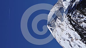 Plane flying above the snowy mountain peak of Pirin mountains, clear blue sky background