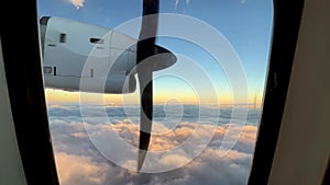 a plane is flying through the clouds at sunset