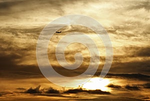 Plane flying over the clouds in a golden sunset