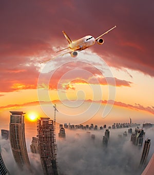 Plane is flying over Dubai against colorful sunset in United Arab Emirates