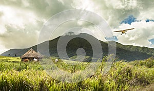 Plane flying over huts in remote tropical location