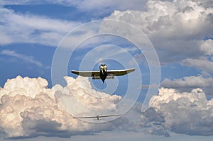 Plane front bottom view with towed glider on cloudy blue sky