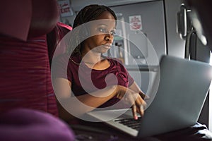 This plane has onboard wifi. an attractive young woman using her laptop while sitting on a plane.