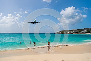 Plane land over people on beach of philipsburg, sint maarten. Jet flight low fly over blue sea. Airplane in cloudy blue sky. Beach