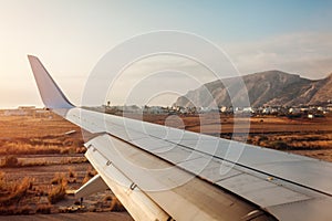 Plane landing in Fira, Santorini island. View of airplane wing. Traveling concept