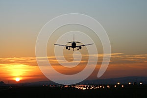 Plane lands at an airfield on the background of sunset