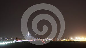 The plane lands at the airport at night.