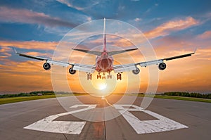 The plane lands on the runway during dawn, rear view from the end of the runway