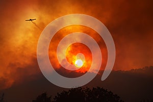 Plane leaving trail of chemicals to fight wildfire against dramatic sunset