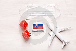 Plane model and face mask and flag Slovakia. Coronavirus pandemic. Flight ban and closed borders for tourists and
