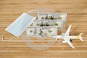 Plane model, face mask and and US dollars money on a wooden background with copy space. resumption of flights. opening of