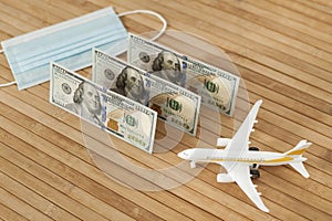 Plane model, face mask and and US dollars money on a wooden background with copy space. resumption of flights. opening of