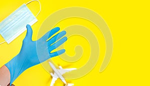 Plane model and face medical mask on a yellow background . Doctor hand with glove