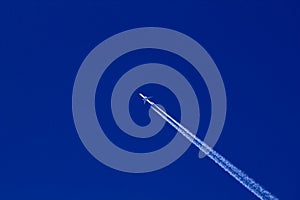 The plane and the plume of white exhaust gases from it against the blue sky