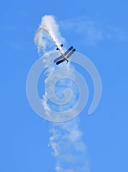 By-plane preforming aerobatics with smoke trail. photo