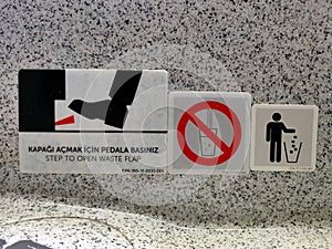 Plane toilet interior sign. Translation: Step to open waste flap sign.