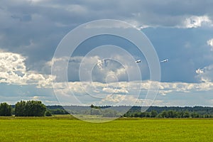 Plane towing a glider after takeoff with a left turn on a background of clouds