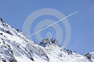 Plane trail over snowy mountain