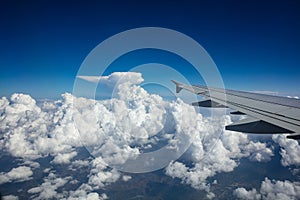 Plane wing on blue cloudy sky background