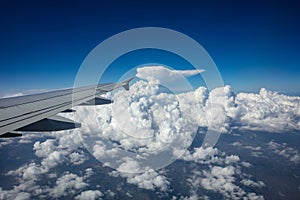 Plane wing on blue cloudy sky background