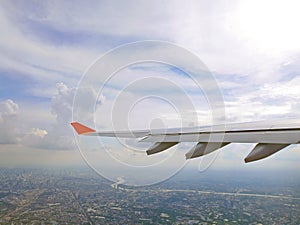 Plane wing and blue sky with city of Bangkok