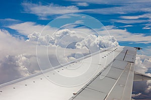 Plane wing, ground, clouds and sky