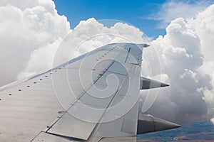 Plane wing, ground, clouds and sky