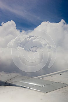 Plane wing, ground, clouds and sky