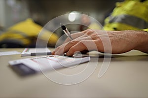 Planer holding black pen and placing his hand on top of personal safety risk assessment take five booklet on the table