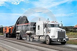 Planer removing a layer of asphalt and tranferring it to a dump truck