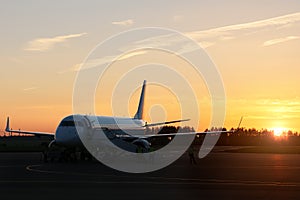 Planes on runway at sunset in airfield take off and prepare to flight.