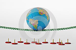 Planet earth balancing on rope over push pins - Concept of health planet and environmental risks