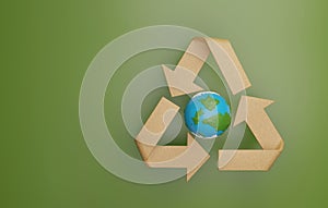 Planet earth with cardboard recycling arrows on green background