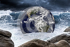 Planet earth globe in thunderstorm wave of water in the rough ocean. Climate change global warming concept on sea background.